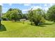 Large backyard featuring lush green grass, mature trees, and a shed in a serene setting at 321 E Taylor St, Landis, NC 28088