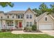 Charming two-story home with a red front door, inviting porch, attached garage, and well manicured landscaping at 5832 Lagrande Dr, Charlotte, NC 28269