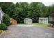 View of a spacious backyard with two storage sheds and gravel driveway at 6213 Golden Oak Ln, Denver, NC 28037