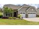 Charming home exterior boasts a well-manicured lawn, stone accents, and a two-car garage at 8035 Pastime Ln, Clover, SC 29710