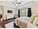 Serene bedroom with a tray ceiling, natural light, hardwood flooring, and a mounted television at 8035 Pastime Ln, Clover, SC 29710