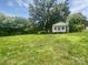 View of the exterior shed in a grassy backyard with mature trees at 908 Mccollough St, Statesville, NC 28677