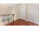 Upstairs hallway featuring hardwood floors, a railing overlooking a window, and two white doors at 10129 Loch Lomond Dr, Charlotte, NC 28278