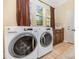 Well-lit laundry room featuring tile flooring, modern appliances, and ample cabinet space at 10129 Loch Lomond Dr, Charlotte, NC 28278