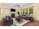 Bright living room with a fireplace, many windows, a ceiling fan, and cozy gray furniture at 10129 Loch Lomond Dr, Charlotte, NC 28278