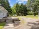 Expansive backyard showcasing a stone patio, gravel driveway, and mature trees, offering a serene outdoor setting at 1025 Old Us 80 Hwy, Gold Hill, NC 28071