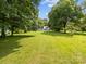 Expansive green space showcasing the home in the distance, surrounded by mature trees and lush greenery at 1025 Old Us 80 Hwy, Gold Hill, NC 28071