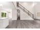Open-concept living room with gray wood floors, a staircase, and a view into the kitchen and dining area at 1471 Marshbrooke Ln, Catawba, NC 28609