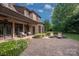 Relaxing outdoor patio featuring comfortable seating areas, stone pavers, and beautifully landscaped backyard with white flowers at 1500 Lookout Cir, Waxhaw, NC 28173