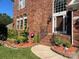 A close up view of a well manicured brick home with beautiful landscaping and an arched front door entryway at 15811 Burlingame Dr, Huntersville, NC 28078