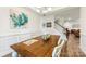 Well-lit dining room with a wooden table, white chairs, decorative artwork, and access to the staircase at 2439 Judson Dr, Gastonia, NC 28054