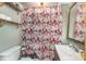 Small bathroom features a sink, toilet, and a shower with a patterned curtain and convenient storage shelves at 300 S Hudson Ave, Spencer, NC 28159
