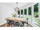 Dining room with a modern chandelier, rustic table, and large windows showcasing lush outdoor views for a serene dining experience at 316 Wade Hampton Dr, Matthews, NC 28104