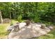 Backyard firepit area surrounded by mature trees and natural seating, perfect for entertaining at 322 Ethan Ln, Rock Hill, SC 29732