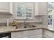 Close up of a kitchen sink with white cabinets, granite countertops, and subway tile backsplash at 4000 Garfield Ct, Waxhaw, NC 28173