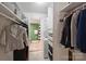 Organized walk-in closet featuring built-in shelving and adjacent bathroom with stacked washer/dryer at 4736 Hedgemore Dr, Charlotte, NC 28209