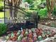 Community entrance featuring a wrought iron gate, colorful flowers, and lush landscaping at 4736 Hedgemore Dr, Charlotte, NC 28209
