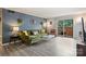 Bright living room featuring a stylish green sofa and sliding glass door to the outdoor brick-wall patio at 4736 Hedgemore Dr, Charlotte, NC 28209