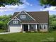 Charming craftsman-style home with blue siding, stone accents, a welcoming front porch, and a well-maintained lawn at 5205 Raging Creek Dr # 122, Indian Trail, NC 28079