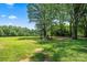 Expansive land with a lush green field and mature trees under a blue sky at 5740 Crouse Rd, Crouse, NC 28033