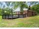 Backyard view showing wooden deck with black railing, brick house with white siding, and lush greenery at 5811 Gettysburg Dr, Concord, NC 28027