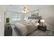 A modern bedroom with neutral paint, ceiling fan, a gray upholstered headboard, and side tables at 5811 Gettysburg Dr, Concord, NC 28027
