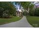 Classic brick home with a long driveway, surrounded by mature trees and lush greenery at 5811 Gettysburg Dr, Concord, NC 28027