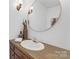 Stylish bathroom features a wood vanity, a large round mirror, and modern fixtures at 629 Wingrave Dr, Charlotte, NC 28270