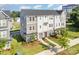 Stylish townhome featuring mixed siding and stonework details, with a well-manicured lawn, shrubbery, and blue skies at 7012 Bryce Ave, Charlotte, NC 28217