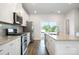 Bright kitchen boasts white cabinetry, granite counters, stainless steel appliances, and a sliding glass door to the balcony at 7012 Bryce Ave, Charlotte, NC 28217