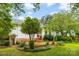 This backyard features mature trees, lush green grass and a charming well at 805 S Main St, Mount Holly, NC 28120
