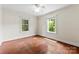 Bright bedroom with hardwood floors, ceiling fan, and two windows overlooking green outdoor space at 805 S Main St, Mount Holly, NC 28120