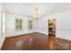 Spacious dining area with hardwood floors, shuttered windows, and an elegant chandelier leading into the well lit kitchen at 805 S Main St, Mount Holly, NC 28120