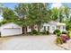 Charming white home with a gravel driveway, mature trees, and a two-car garage offering a blend of comfort and curb appeal at 805 S Main St, Mount Holly, NC 28120