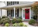 Inviting front porch with rocking chairs, a bright red door, and lush landscaping at 8700 Fox Tail Ln, Huntersville, NC 28078