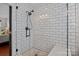 Modern walk-in shower featuring white subway tile, glass door, dark hardware, and built-in bench at 8700 Fox Tail Ln, Huntersville, NC 28078