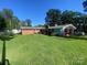 Expansive backyard showing the rear of the house, carport, and lush green lawn under a bright blue sky at 903 Woodside Dr, Kings Mountain, NC 28086