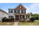 Charming two-story brick home with a welcoming front porch and manicured lawn and a visible American flag at 10349 Alvarado Way, Charlotte, NC 28277