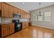 Bright kitchen with stainless steel microwave, stove, wood cabinets, and hardwood floors at 10349 Alvarado Way, Charlotte, NC 28277