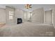Large carpeted living room with a fireplace, ceiling fan, and staircase leading to the second floor at 10349 Alvarado Way, Charlotte, NC 28277