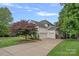Home featuring a three-car garage, mature landscaping, and a well-maintained lawn at 109 Walking Horse Trl, Davidson, NC 28036