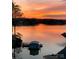 Serene lake view at sunset, casting a warm, orange glow over the waters and boathouse at 14608 Waterside Dr, Charlotte, NC 28278