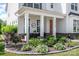 Inviting front porch features decorative columns, a cozy seating area, and lush landscaping at 15103 Keyes Meadow Way, Huntersville, NC 28078