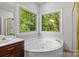 Bright bathroom with jacuzzi tub, glass enclosed shower and a double window at 17433 Glassfield Dr, Huntersville, NC 28078