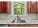 Close-up of the kitchen sink with granite countertops, cherry cabinets and a green backyard view at 17433 Glassfield Dr, Huntersville, NC 28078