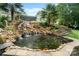 Backyard features rock waterfall flowing into a pond, landscaped with tropical plants at 1912 Dawnhurst Ln, York, SC 29745