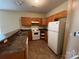 Classic kitchen featuring wood cabinets, white appliances, and neutral countertops at 2012 Ashley Rd, Charlotte, NC 28208