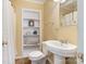 Cozy bathroom with neutral walls, a pedestal sink, open shelving, and stylish decor at 24756 Strand Dr, Albemarle, NC 28001