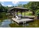 A covered dock sits on the water with a swing, chair, and ladder at 24756 Strand Dr, Albemarle, NC 28001