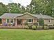 Charming brick home with lush landscaping, inviting front porch, and mature trees at 327 Whitestone Rd, Charlotte, NC 28270